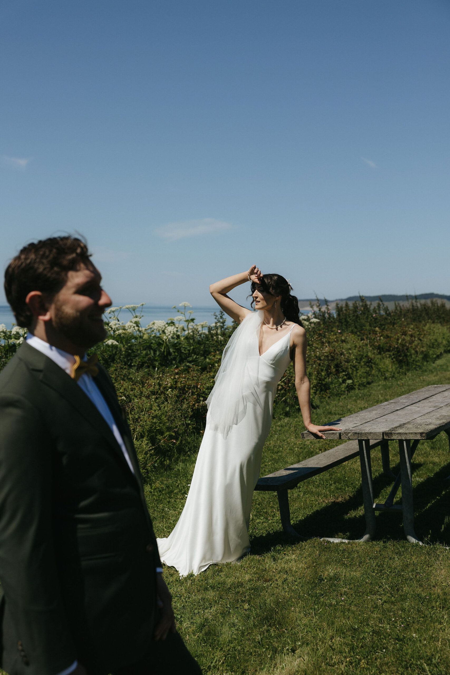 Bride looking off into the distance posing in a white wedding dress and the groom looks in the opposite direction at Whidbey island wedding venue