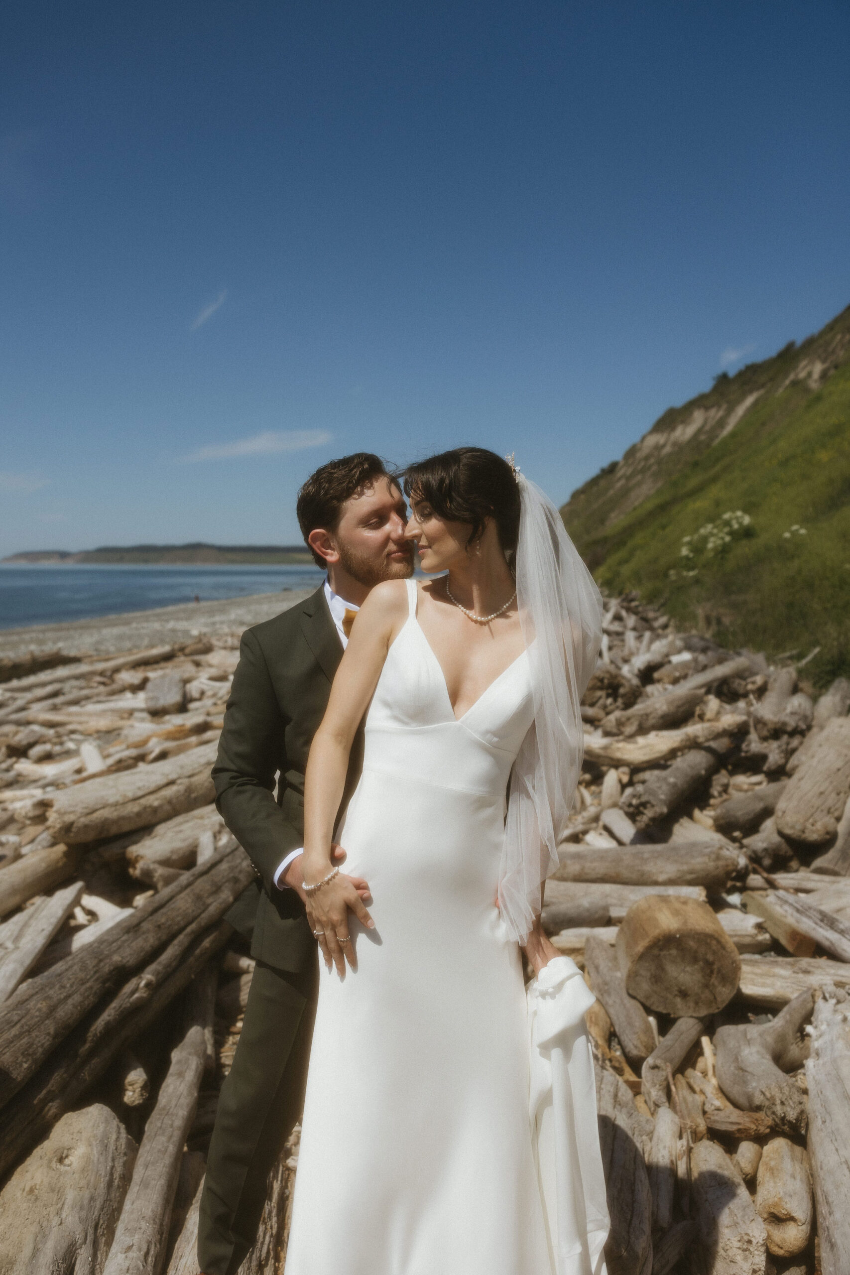 Groom holding bride from behind kissing her cheek at Fort Ebey State Park. 