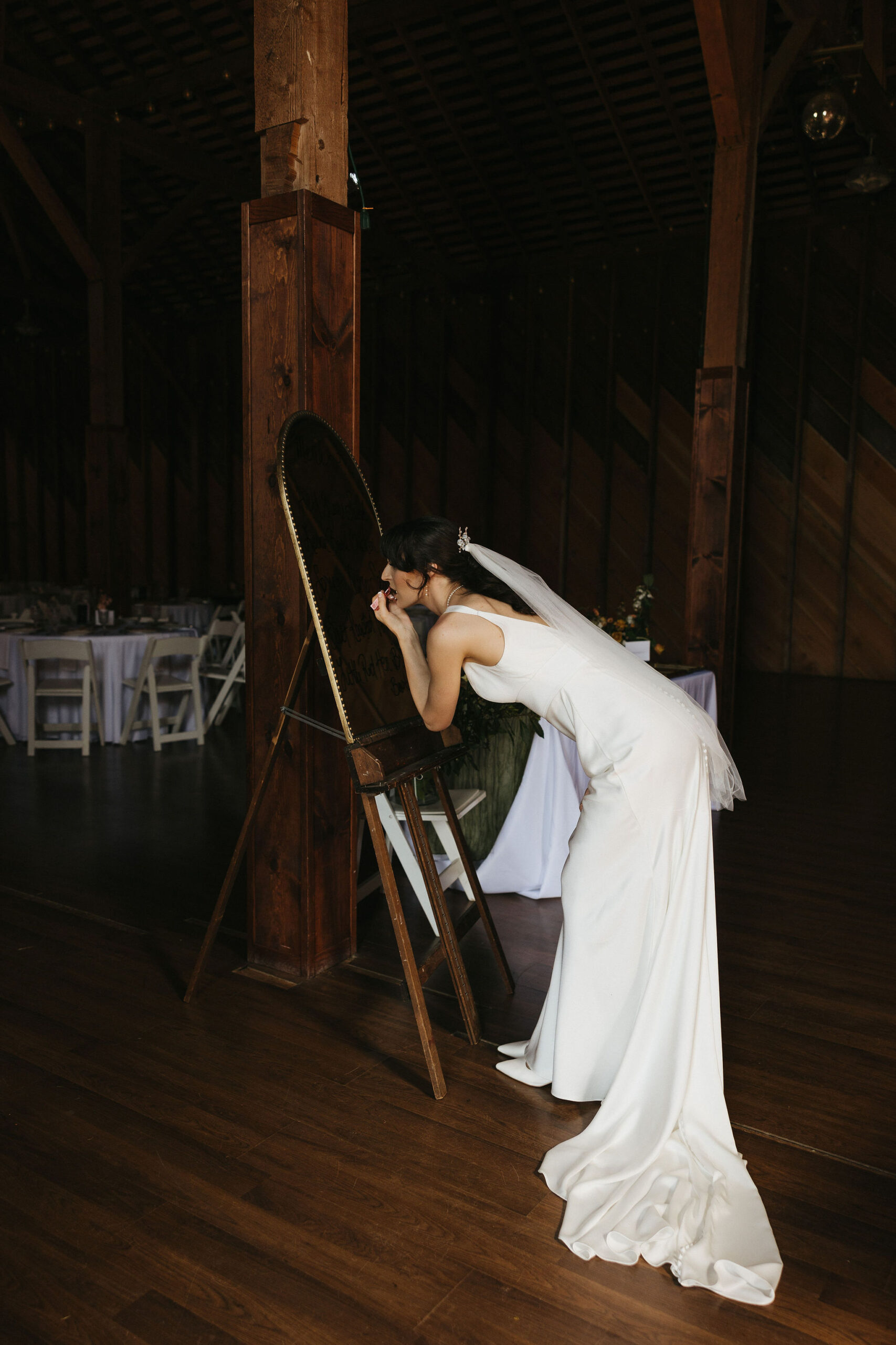 Candid wedding photo of Bride looking into a standing mirror putting lipstick on