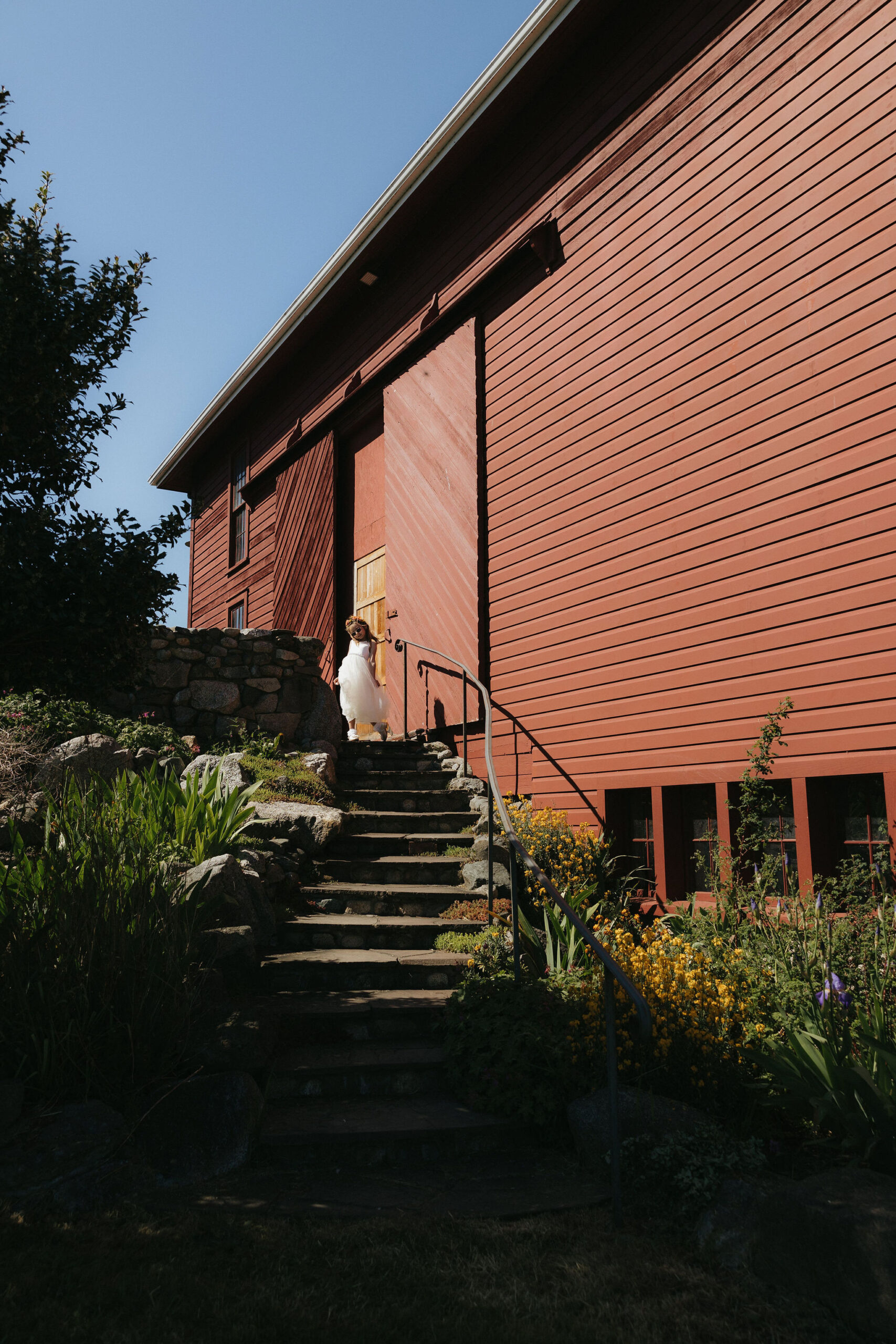 Flower girl walking out from a red barn at Whidbey island wedding venue