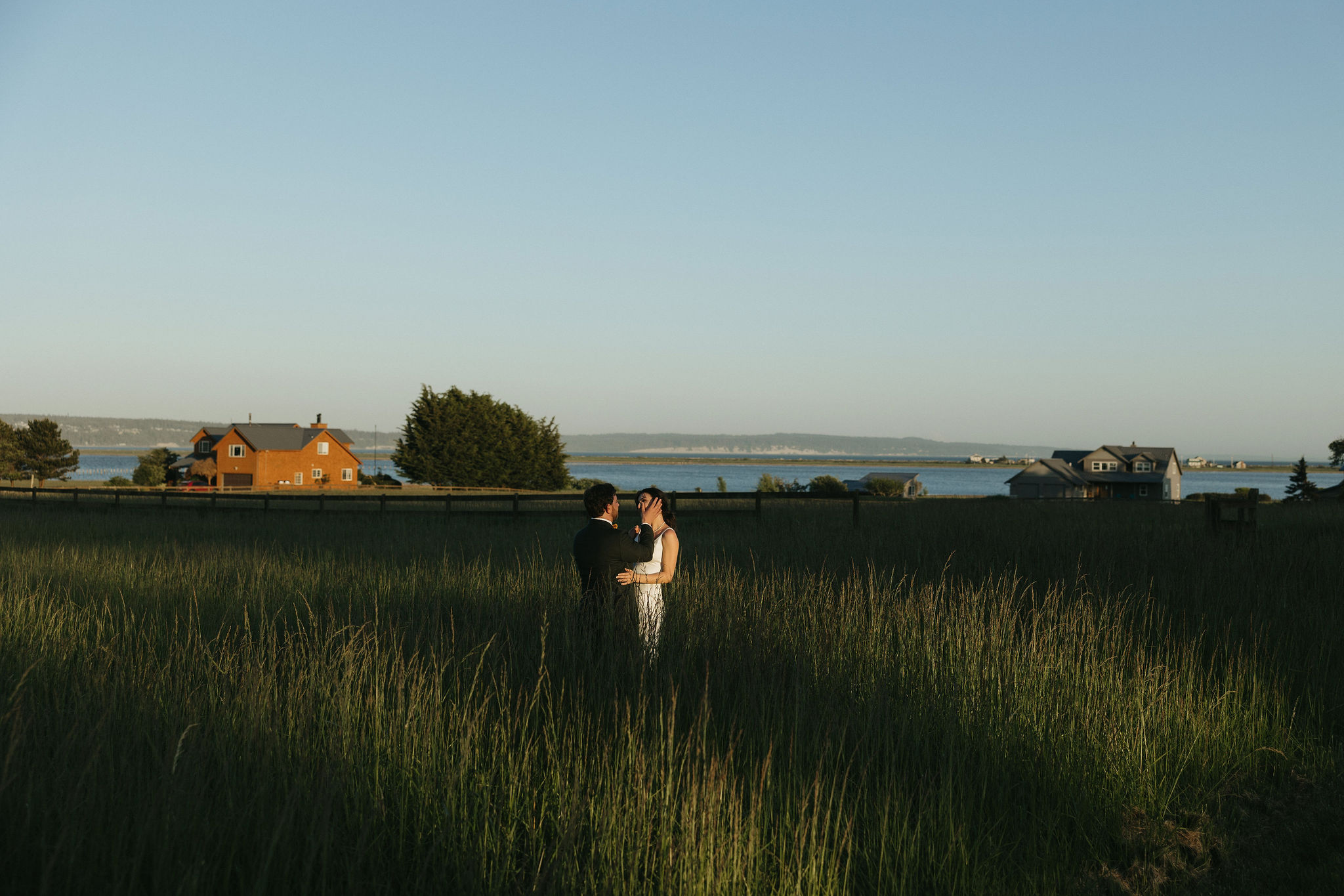 Bride and groom embracing eachother in a grass field at Whidbey island wedding venue