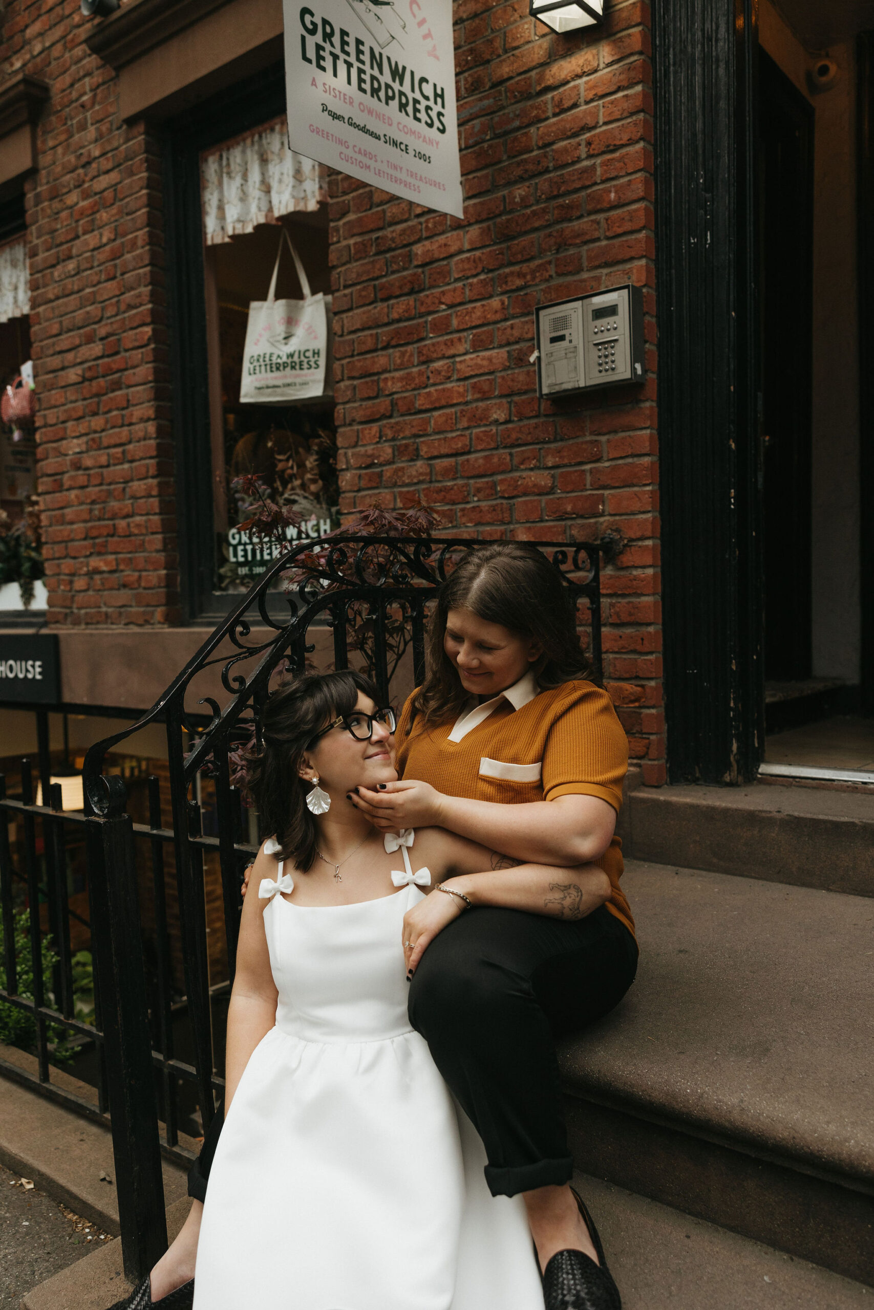 Newly engaged couple sitting in front of a brick house on Cornelia Street in New York