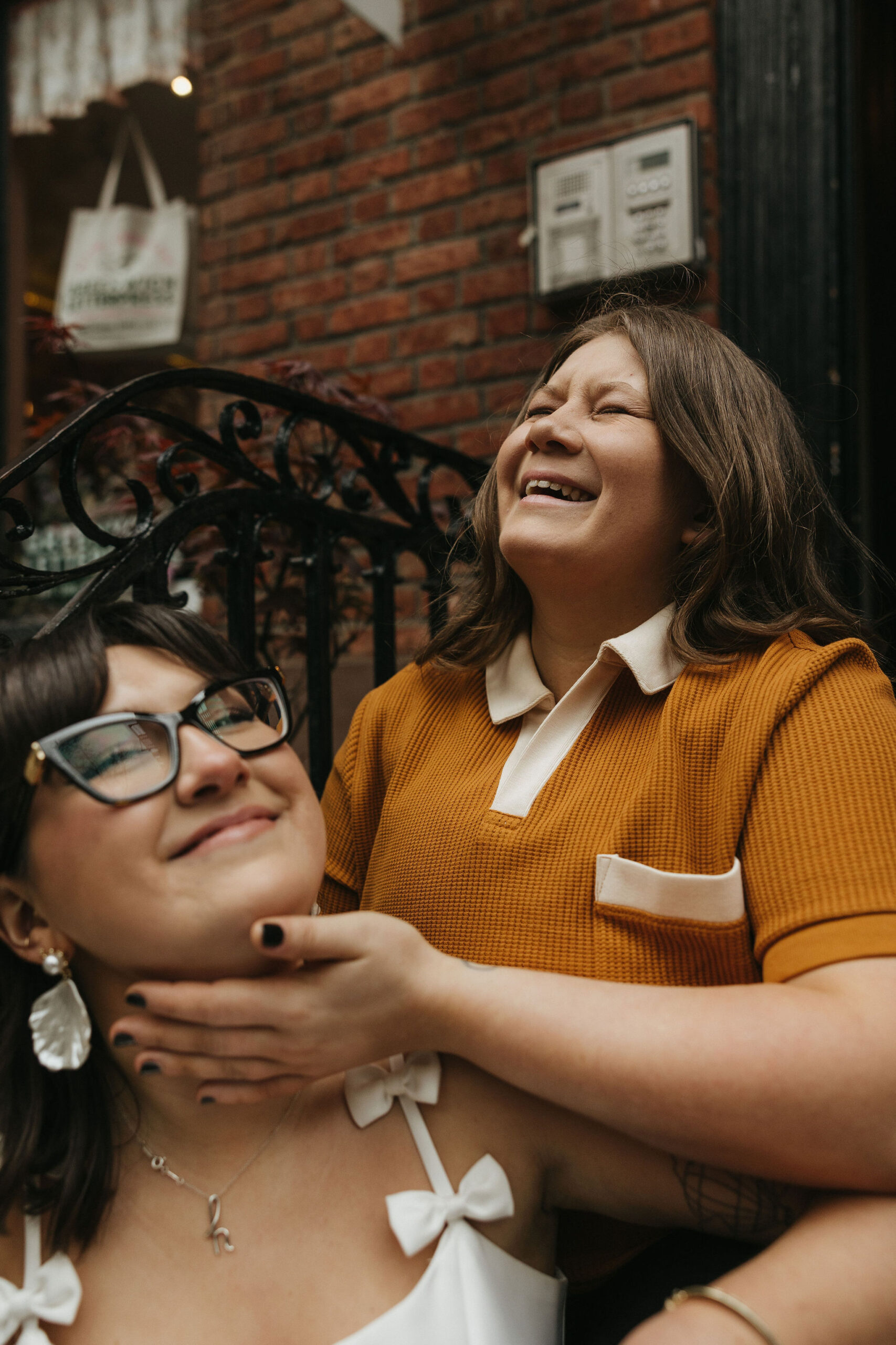 Newly engaged couple sitting in front of a brick house on Cornelia Street in New York