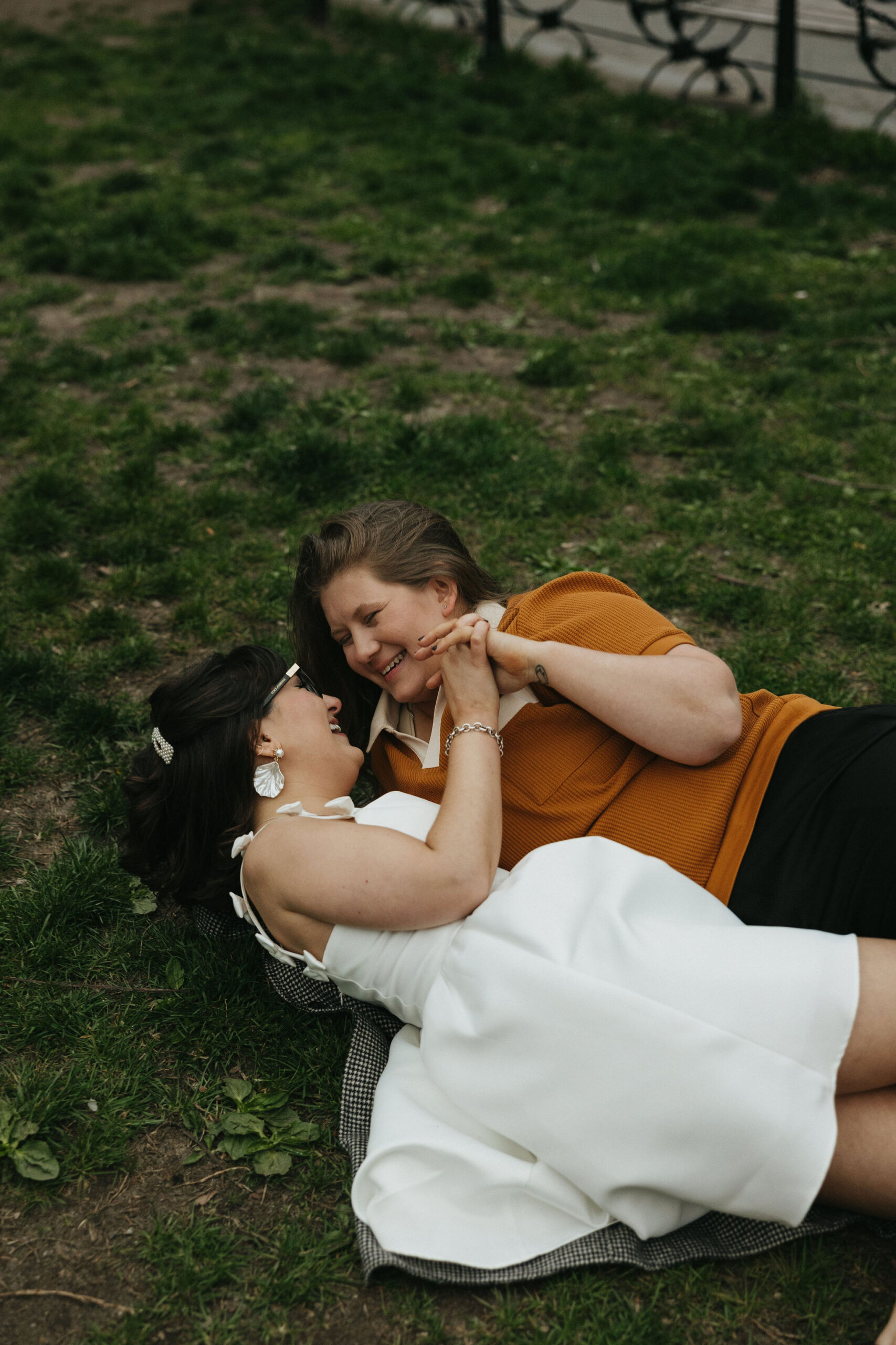 Newly engaged couple laying on grass in New York for their personalized engagement photography