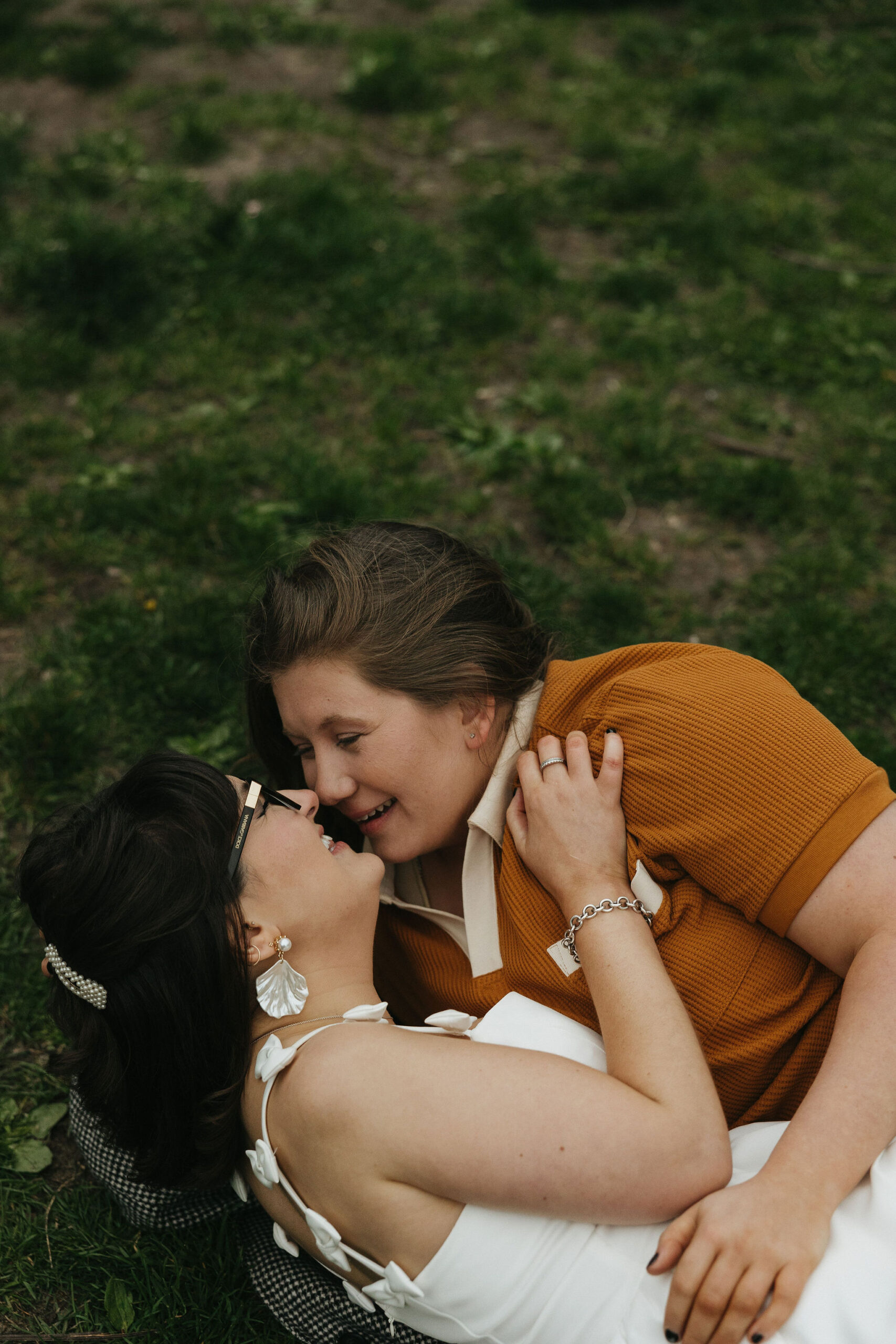 Newly engaged couple laying on grass laughing together in New York for their personalized engagement photography