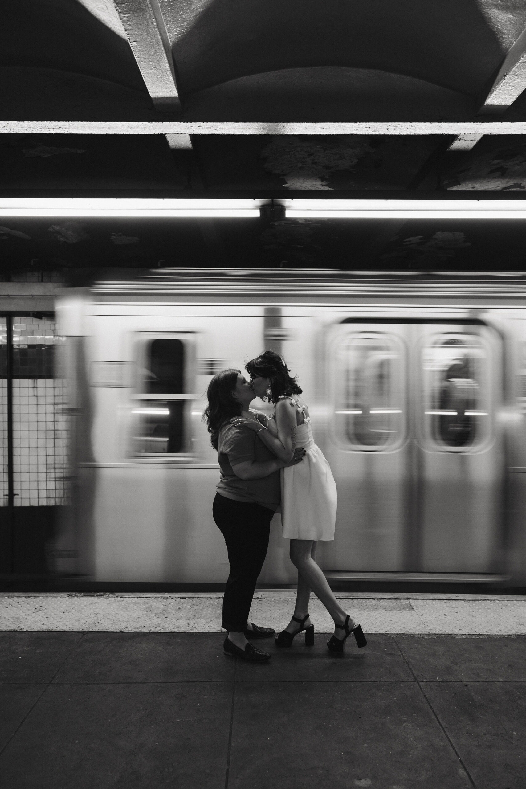 Black and white photo of Newly engaged couple kissing in the New York subways