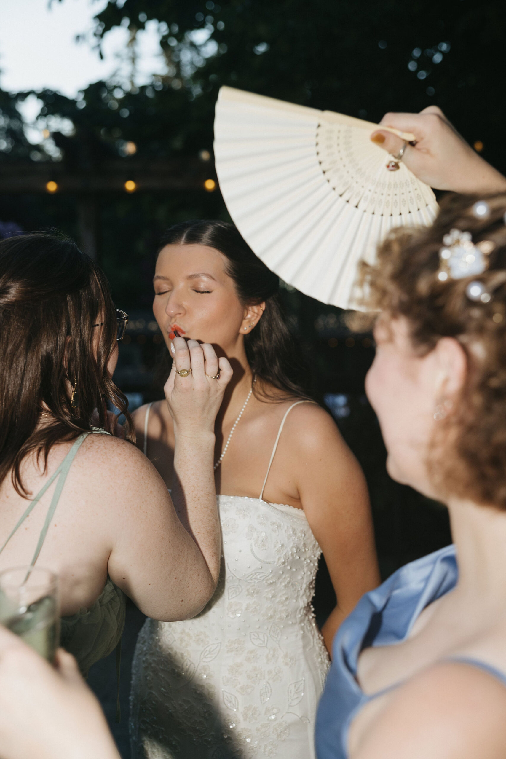 Bridesmaids helping bride put lipstick on 