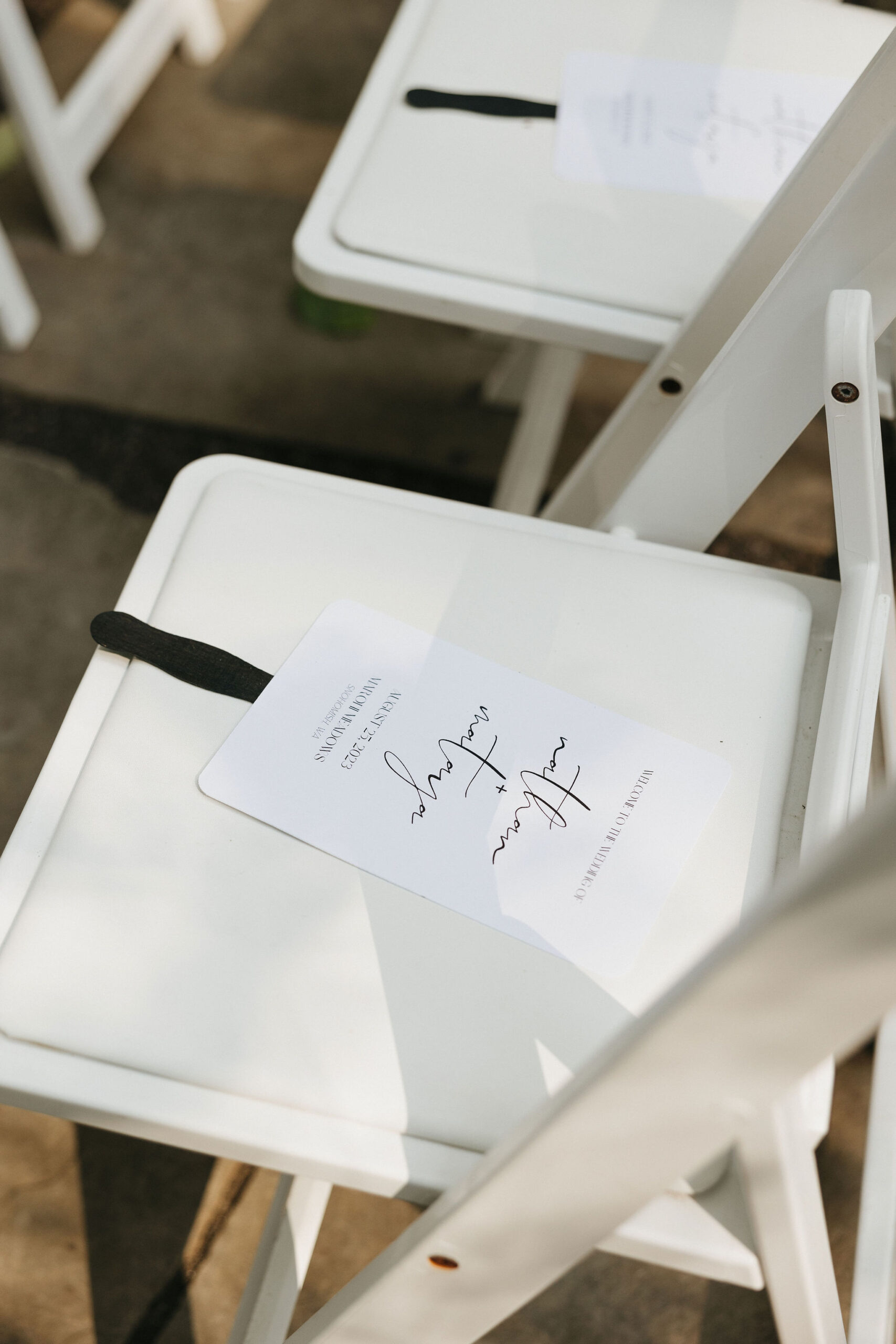 DIY'd wedding invitations placed on a white wedding ceremony seat