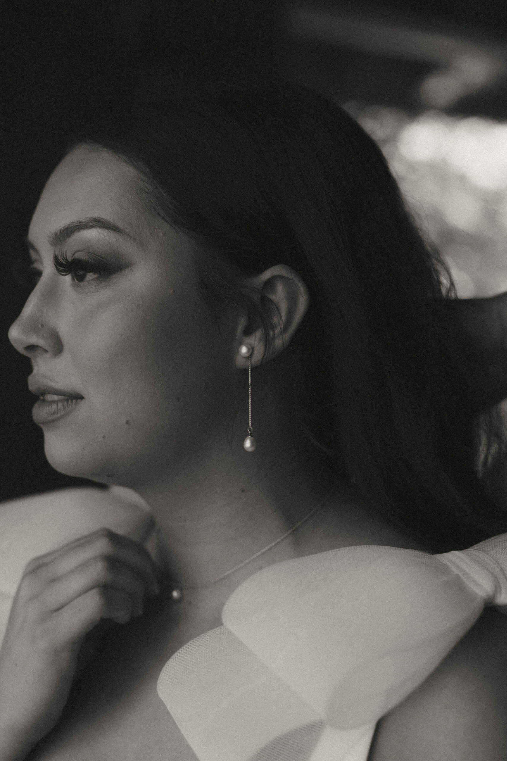 Black and white photo of bride in a white wedding dress wearing pearl earrings 