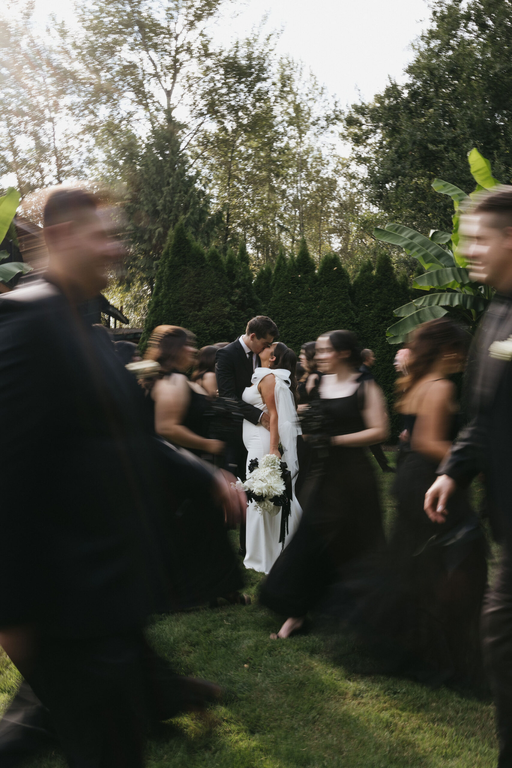 Bride and groom kissing at their bridal party run around them