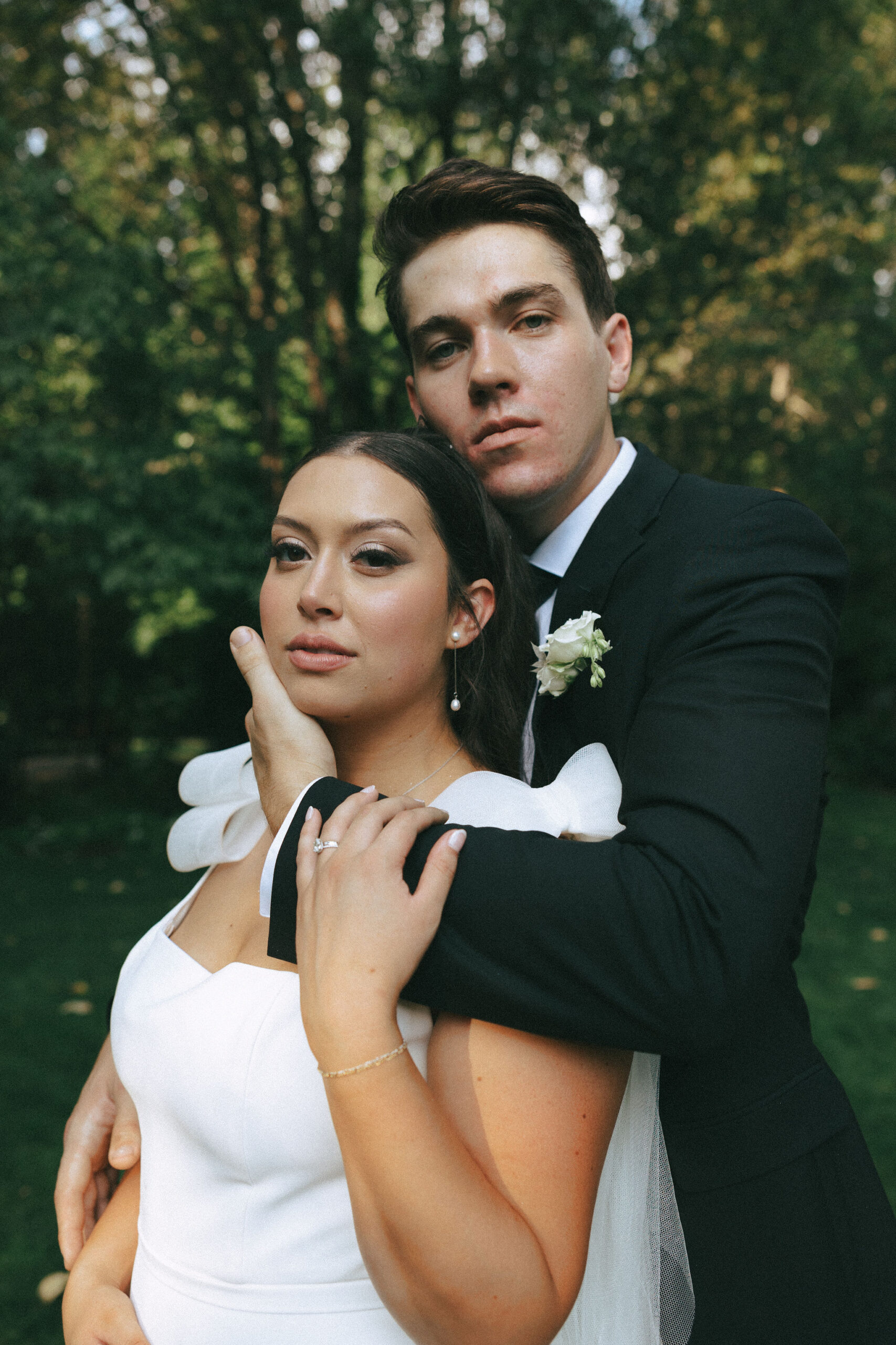 Groom holding bride from behind caressing her face