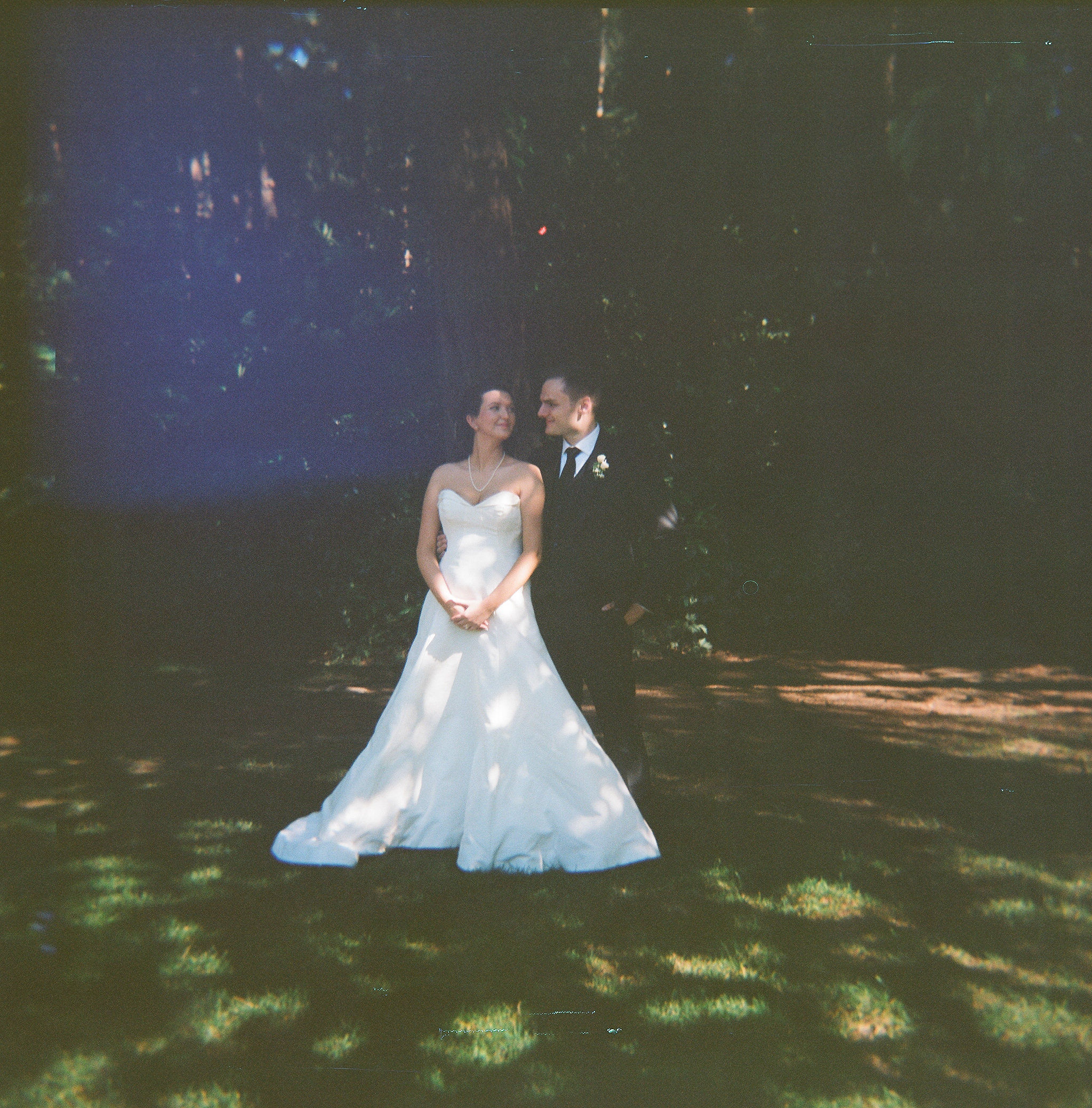 Film photo of bride and groom looking into eachothers eyes on a field of grass at Robinswood House