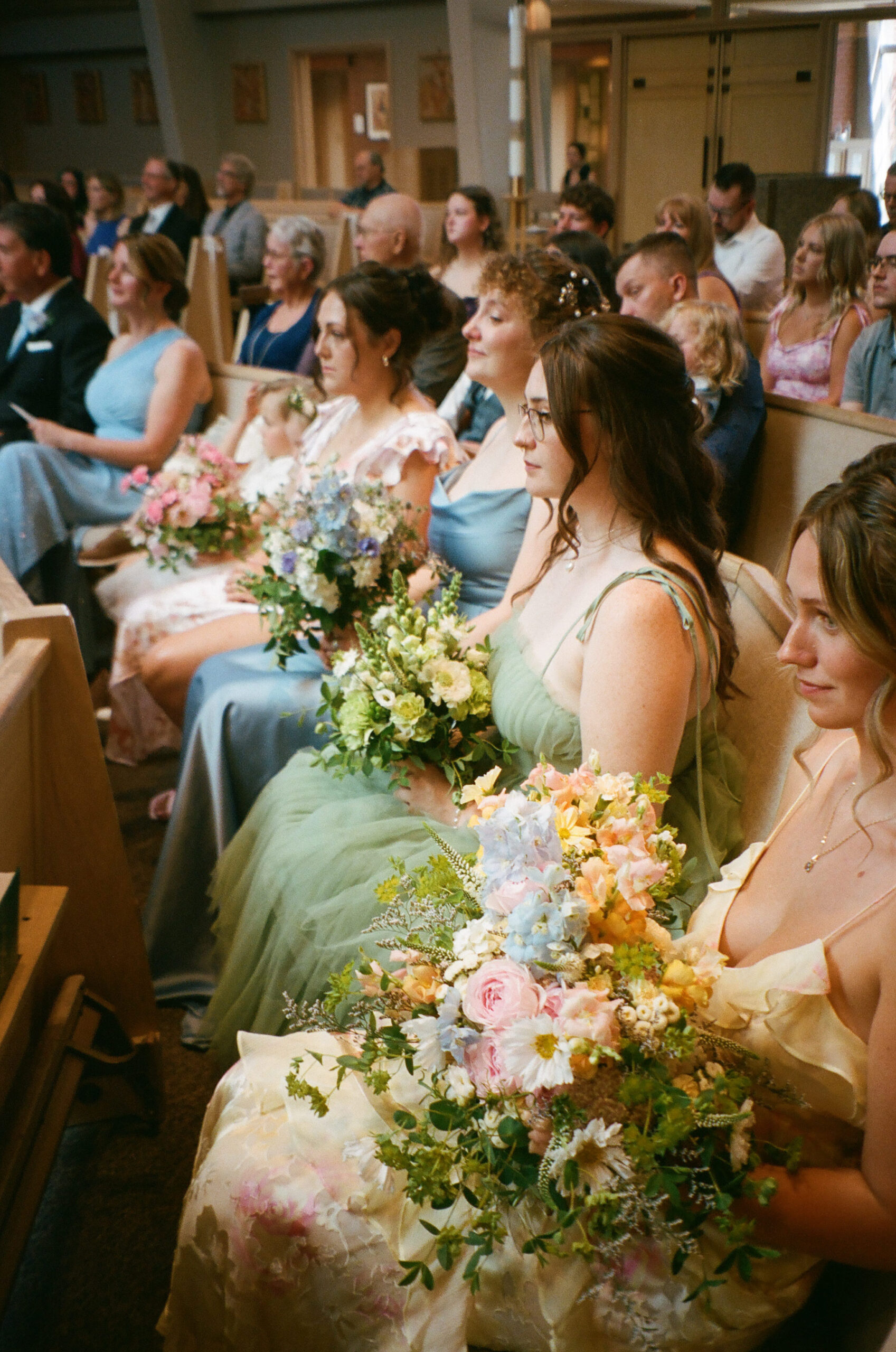 Film photo of guests sitting during the wedding ceremony at the Holy Family Catholic Church