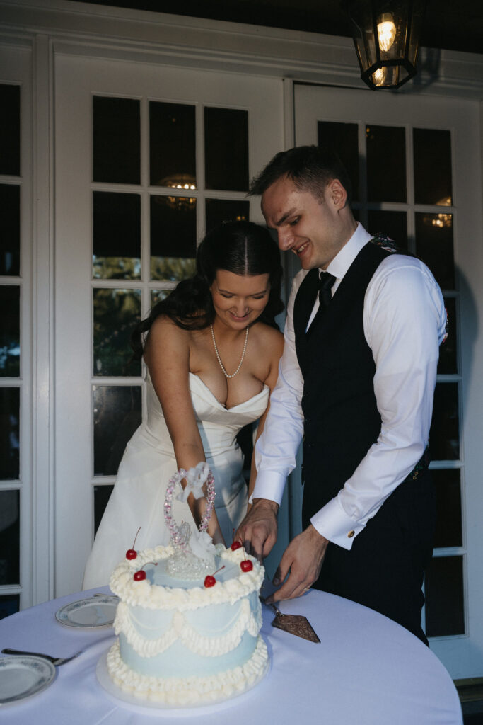 Bride and groom cutting their wedding cake smiling