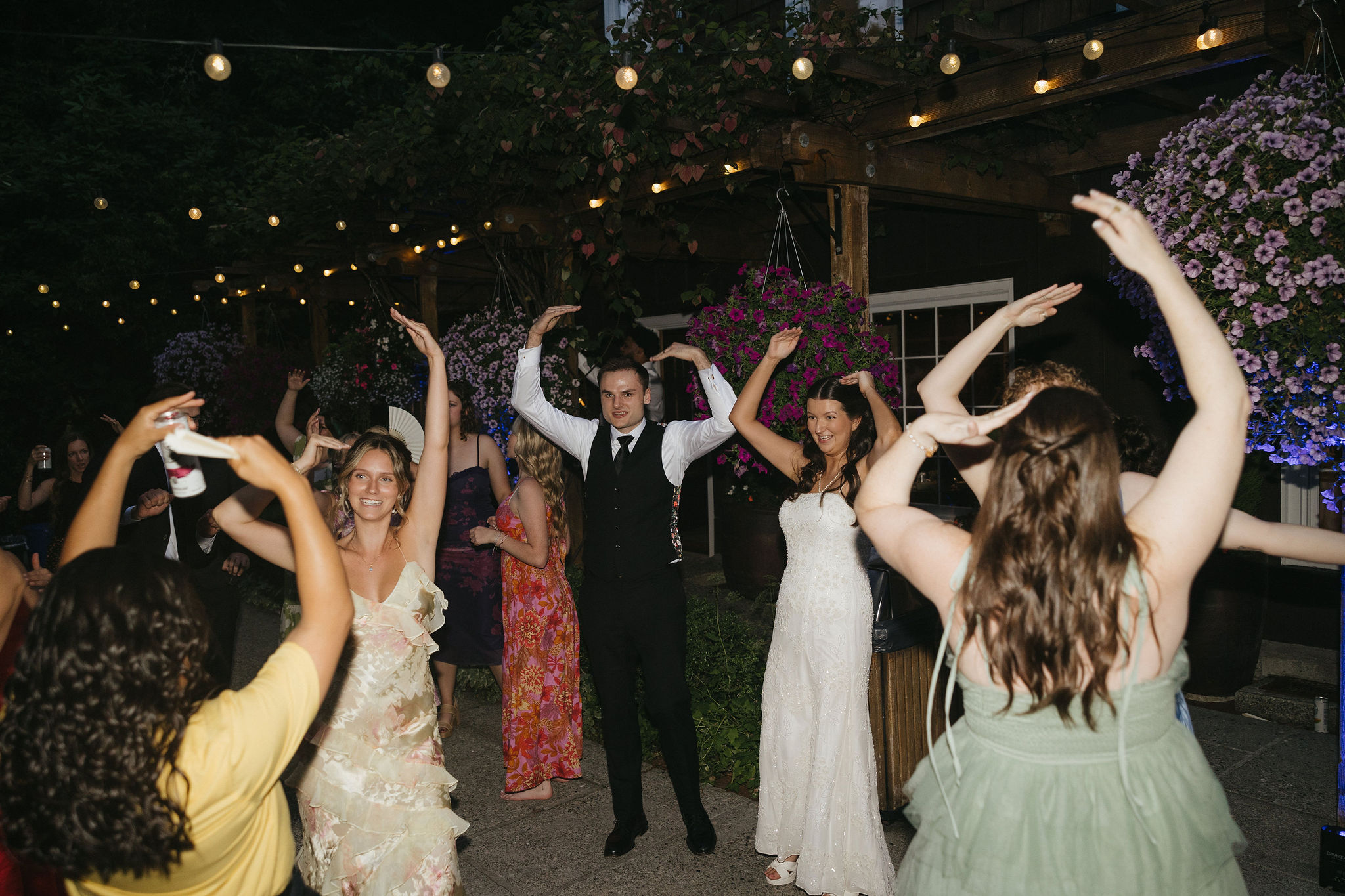 Bride and groom dancing the YMCA during their wedding reception with guests