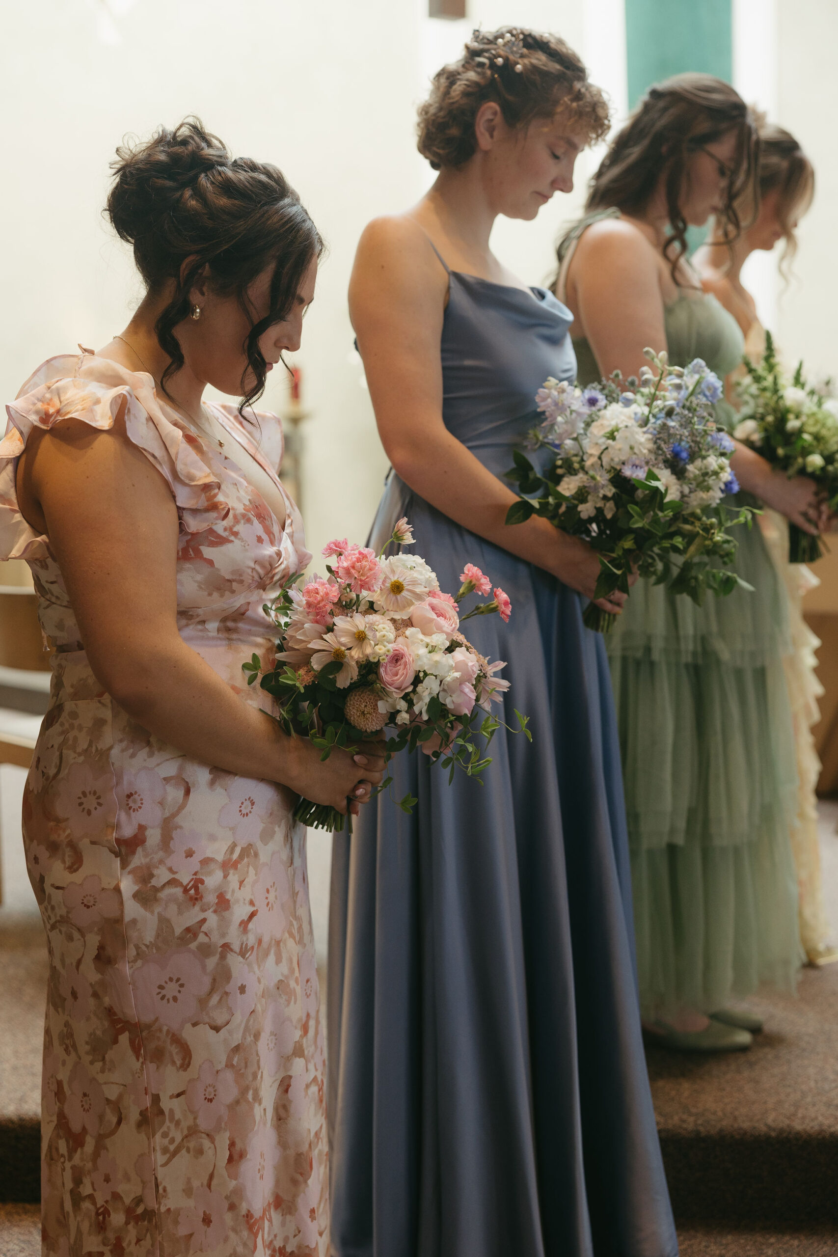 Bridesmaids standing in front during the wedding ceremony bowing their heads in prayer