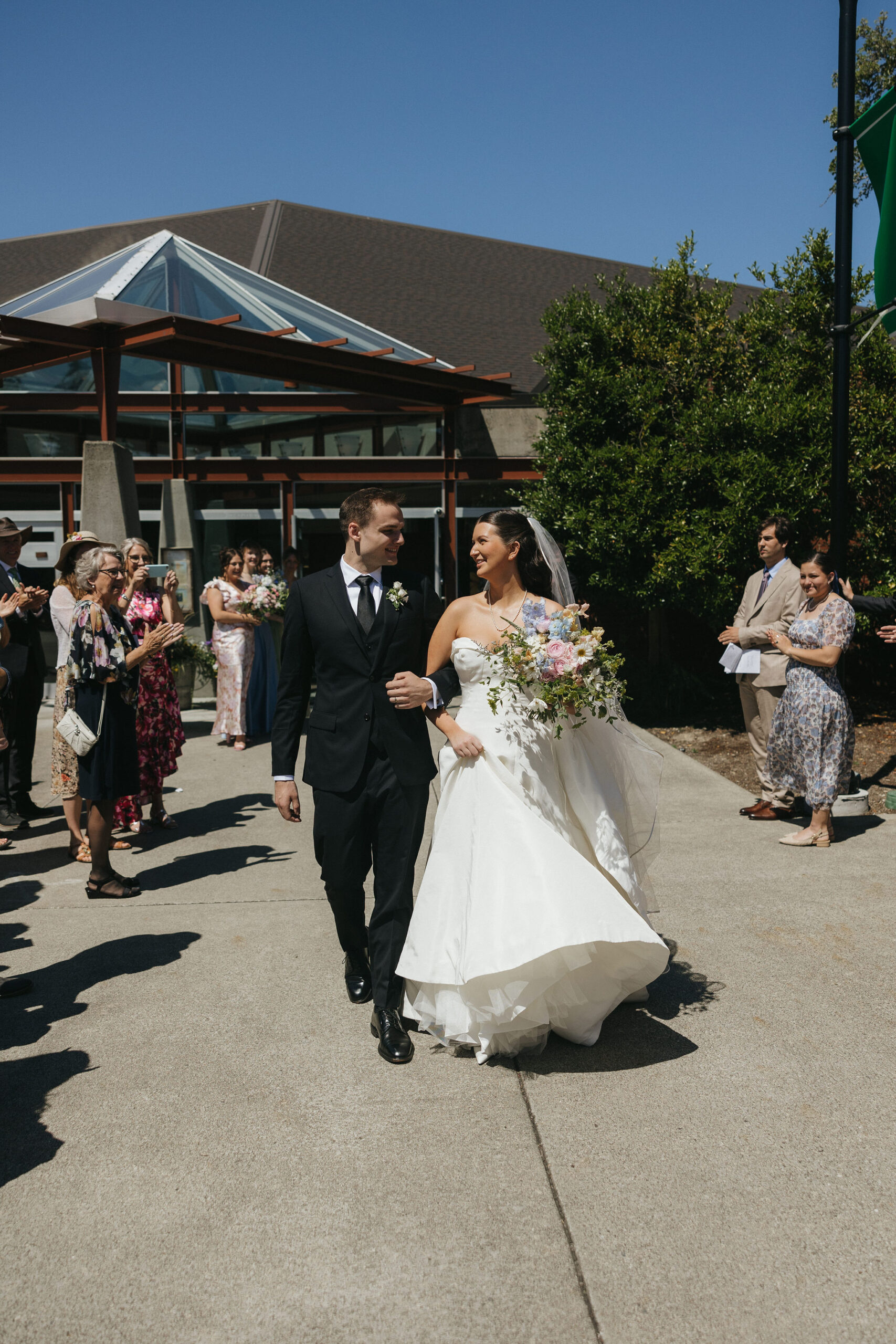 Bride and groom walking out of the church smiling at eachother after their wedding ceremony