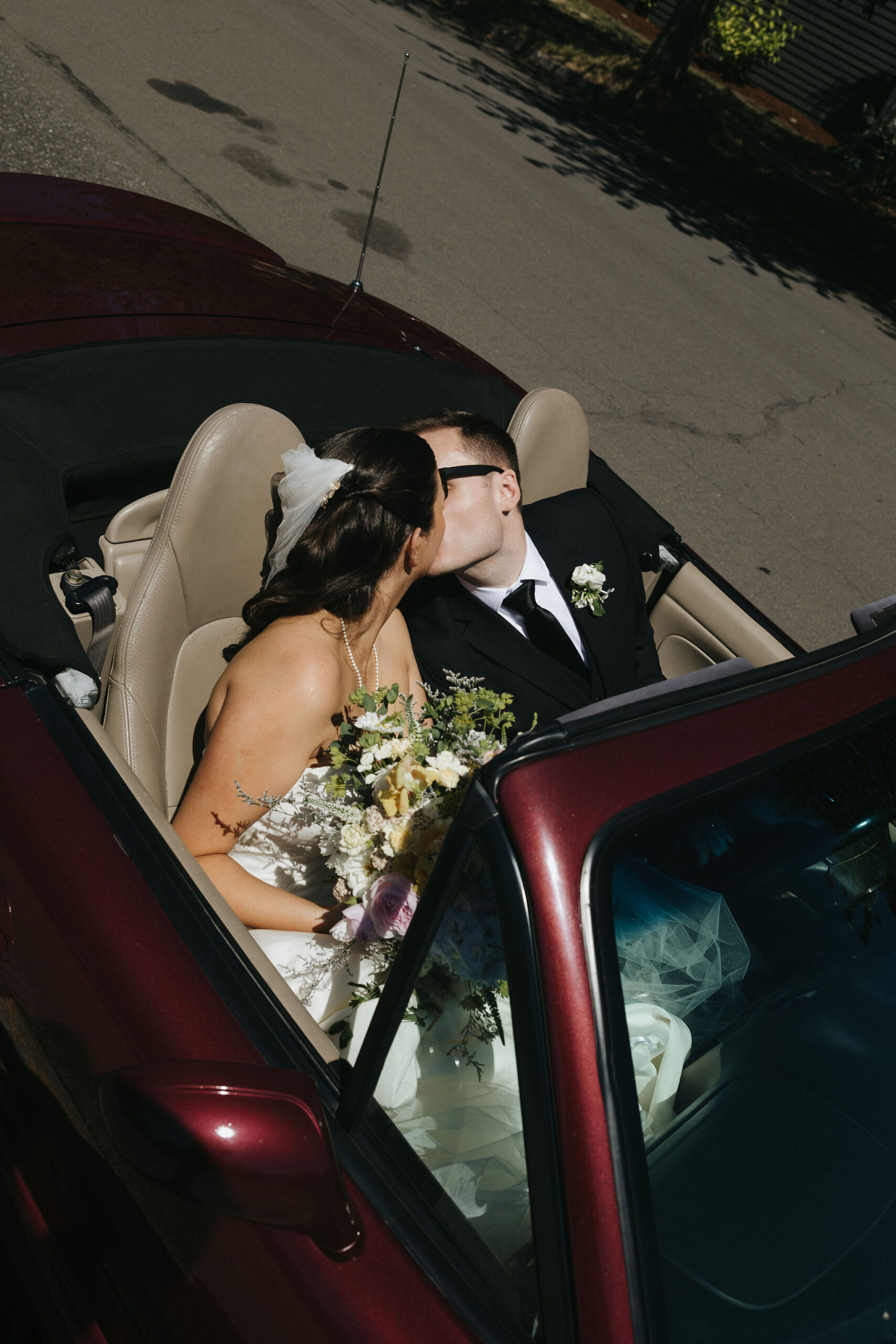 Bride and groom kissing in their getaway car