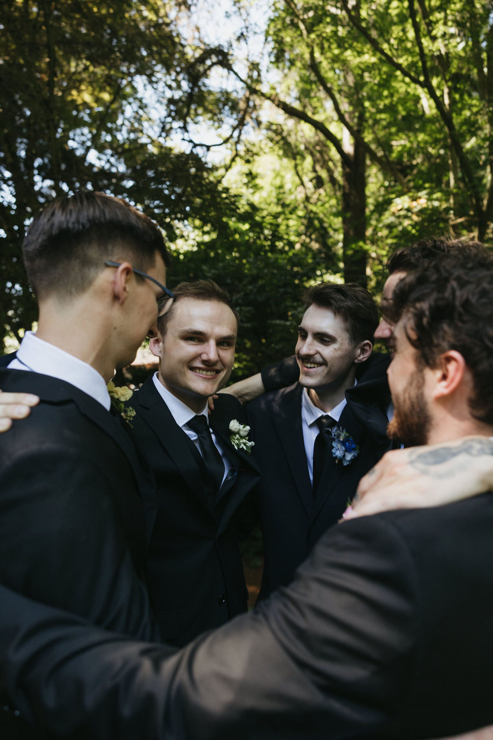 Groom and groomsmen sharing a group hug as they all smile