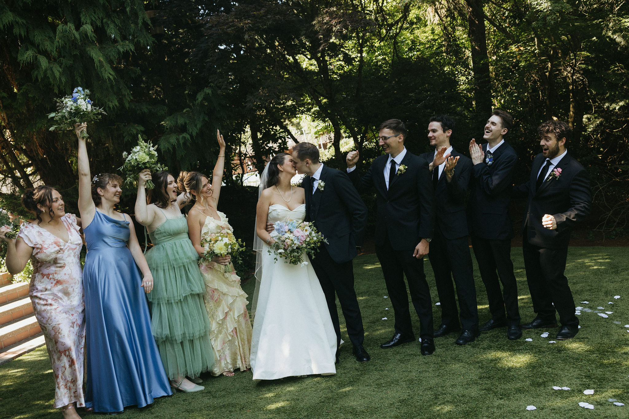 Bride and groom kissing as the bridal party cheers around them