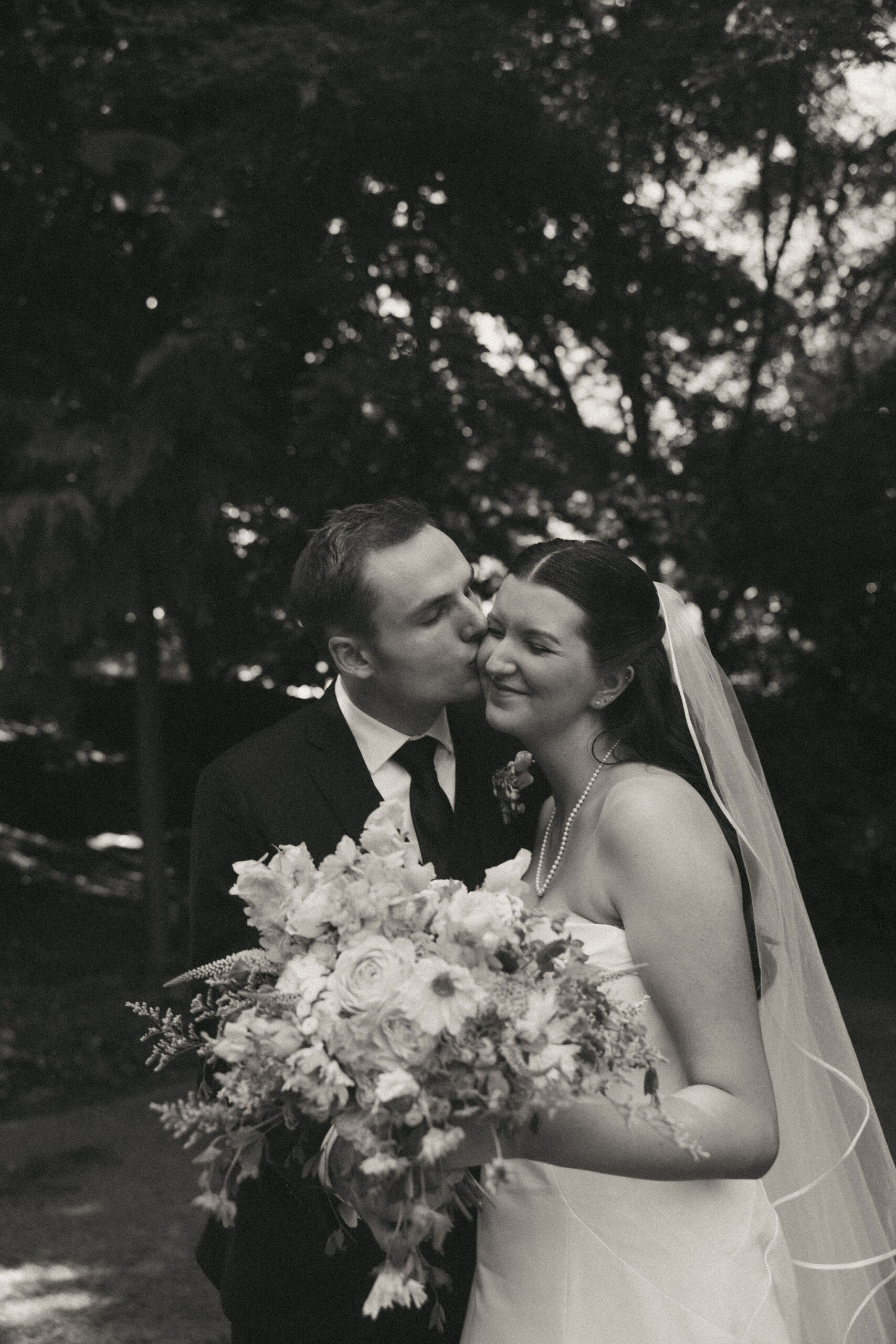 Black and white photo of groom kissing brides cheek