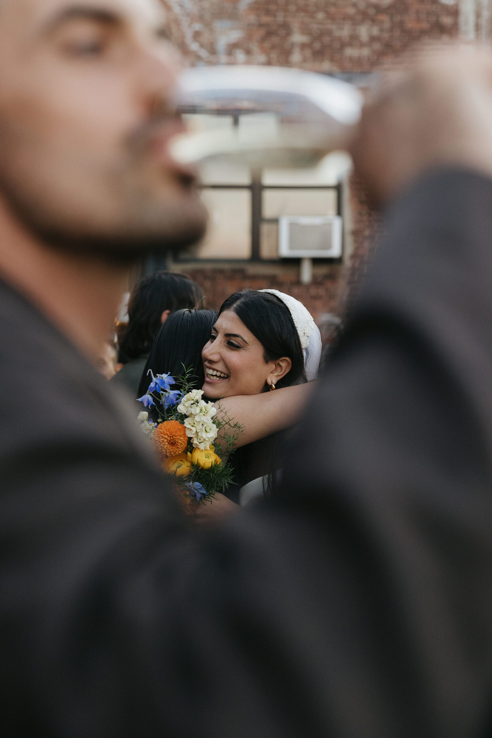 Intimate film wedding photo of the bride hugging a guest, with joyful expressions caught mid-embrace.
