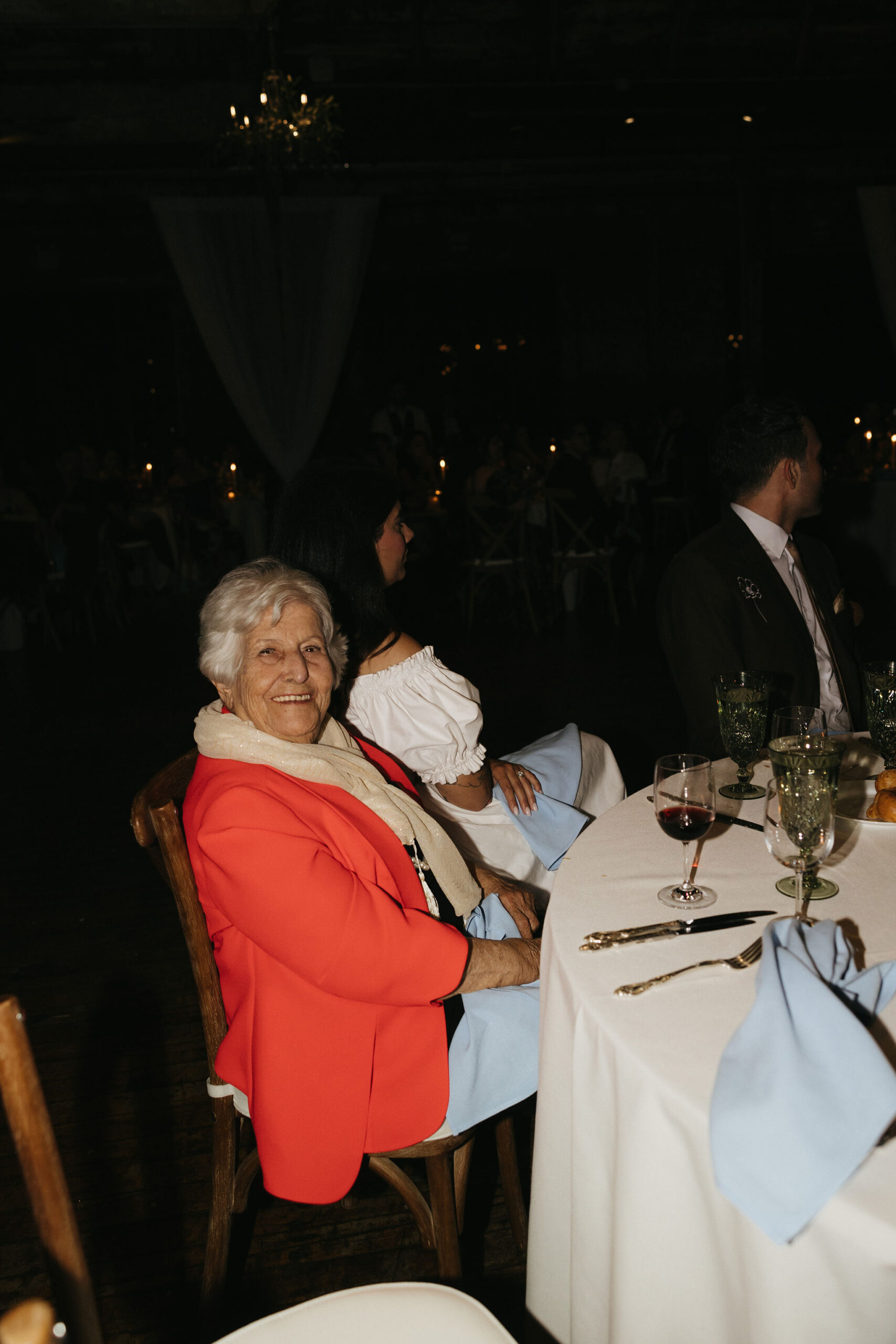 Elderly guest smiling at the wedding reception table, enjoying the festivities.