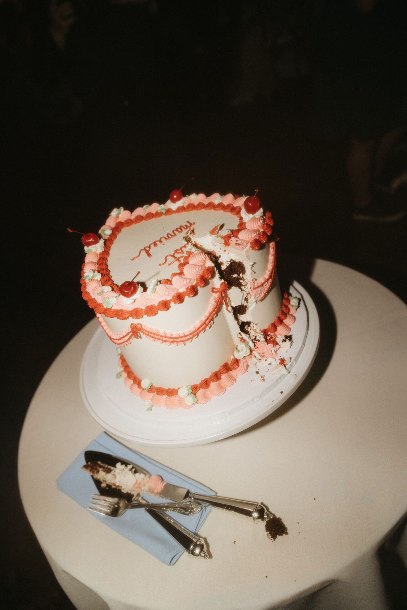 A heart-shaped cake with vintage decorations partially cut at a Greenpoint Loft Wedding, adding a playful, nostalgic vibe to the celebration.