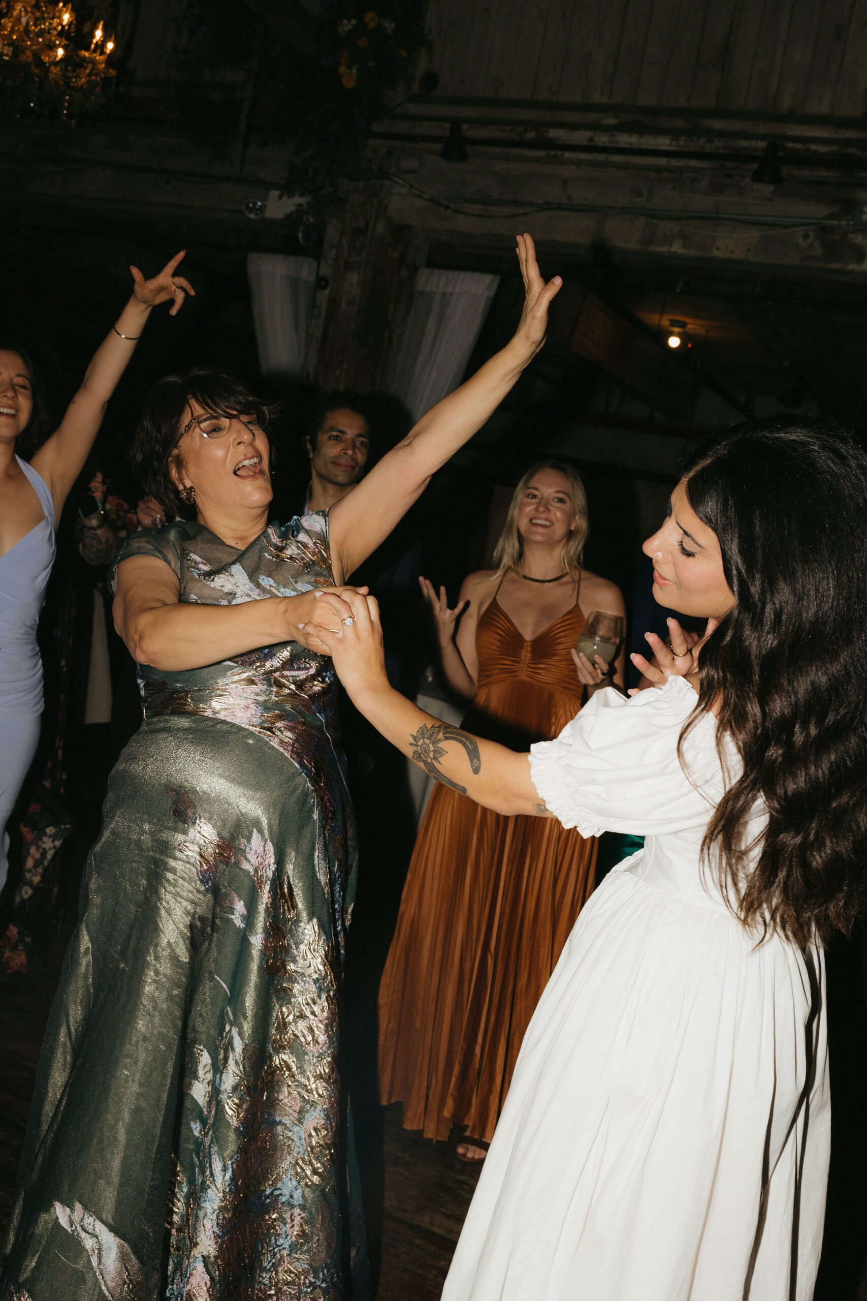 A mother and daughter joyfully dancing together, surrounded by guests enjoying the celebration at a Greenpoint Loft Wedding.