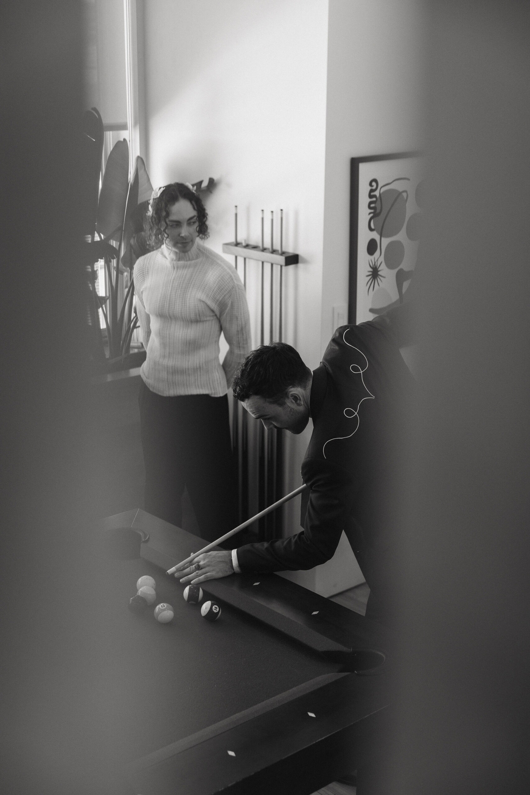 Groom playing pool in a black-and-white candid moment before the Greenpoint Loft Wedding.