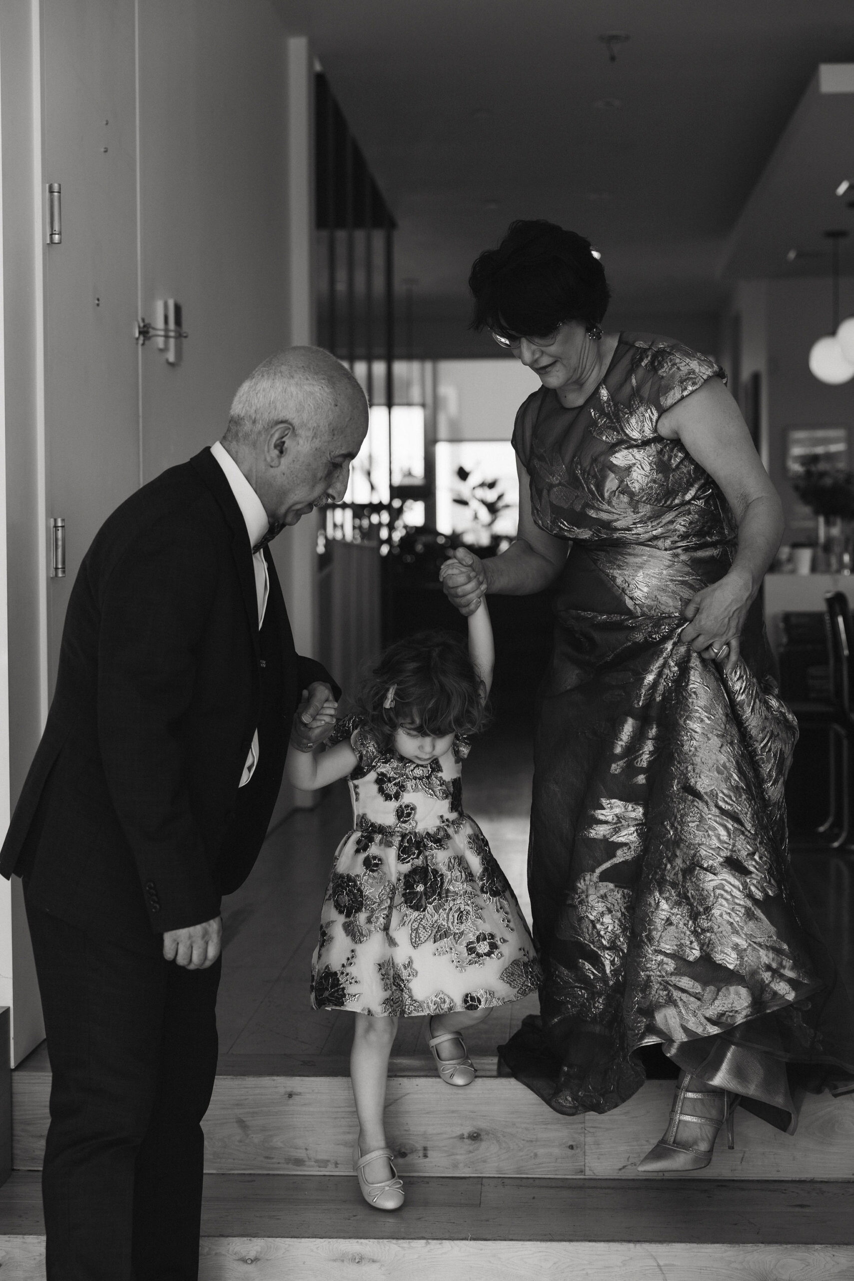 Grandparents helping a child down a step, a candid family moment during the Greenpoint Loft Wedding.