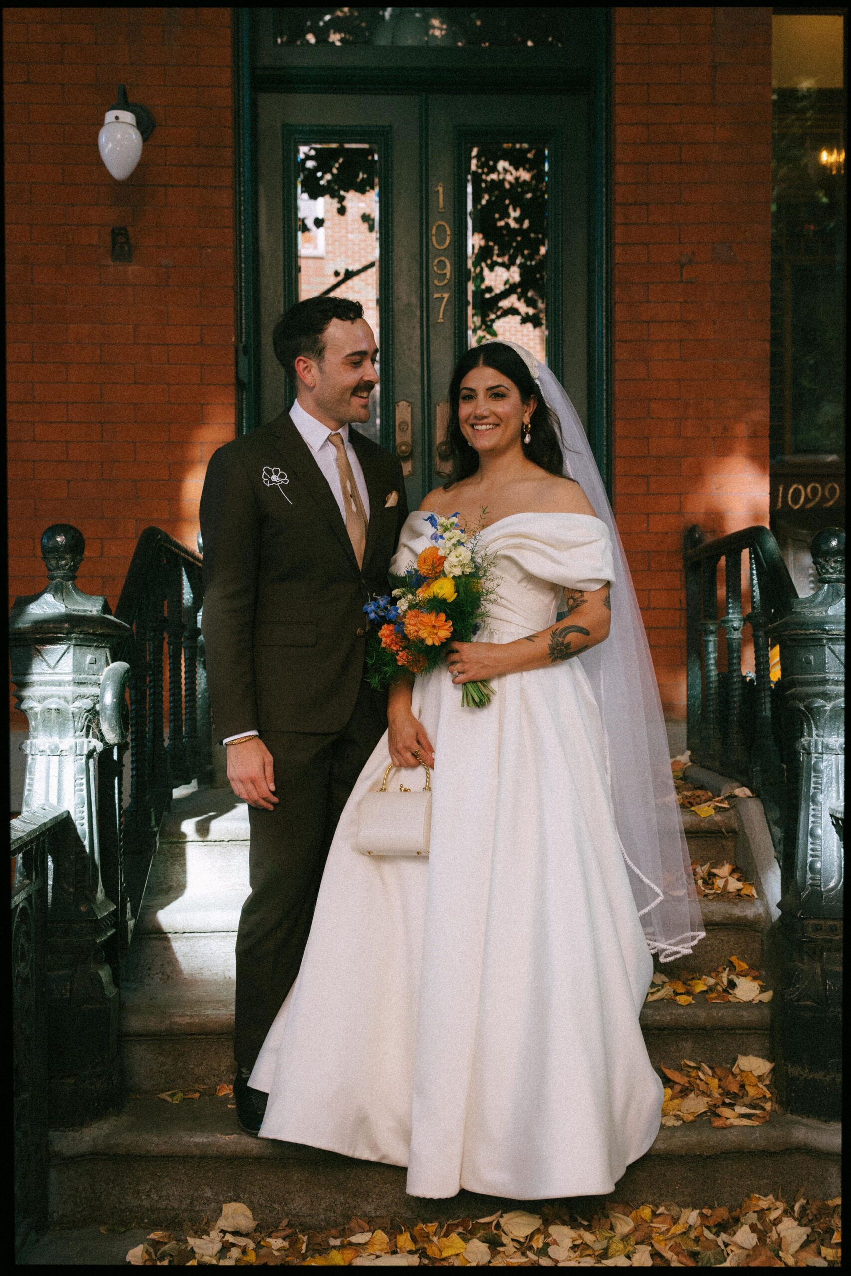 Greenpoint Loft Wedding moment captured as the couple stands outside, bride holding colorful flowers, the groom smiling.
