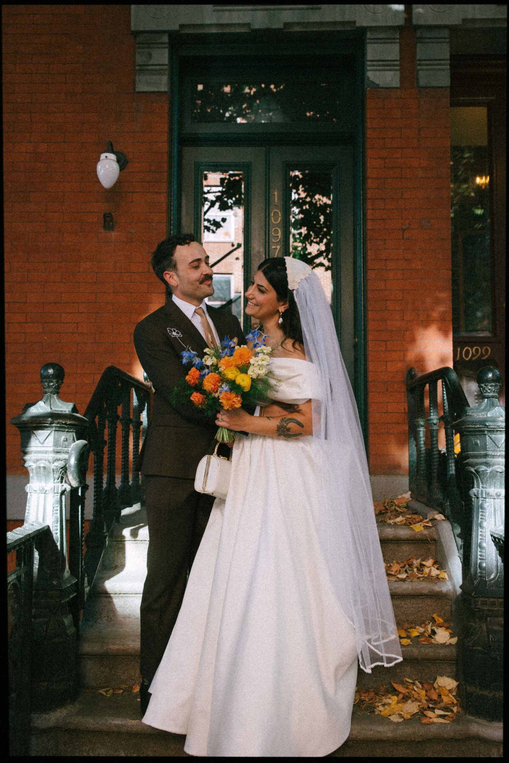 Greenpoint Loft Wedding moment captured as the couple stands outside, bride holding colorful flowers, the groom smiling.