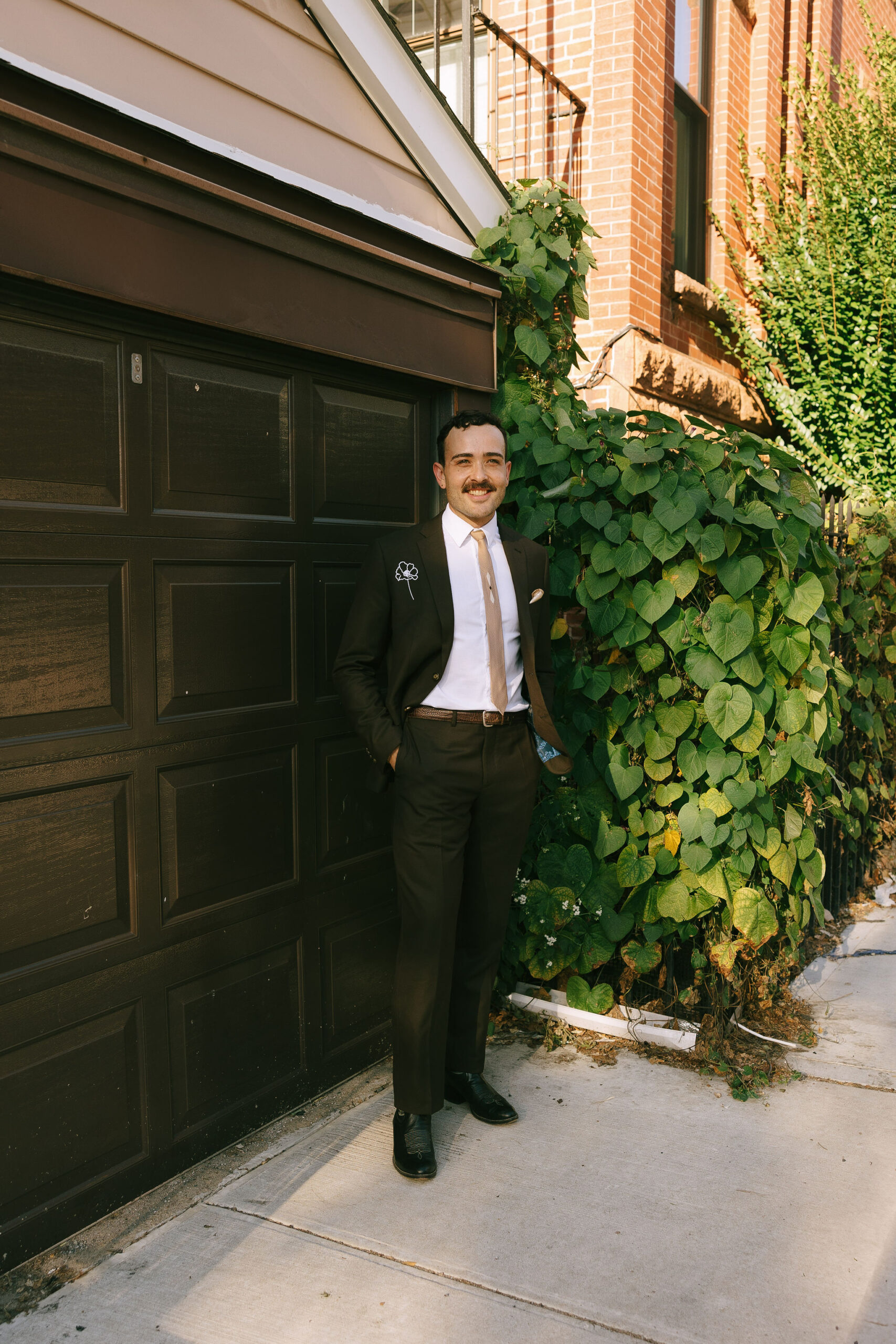 Groom standing outside near greenery, suited for his Greenpoint Loft Wedding.